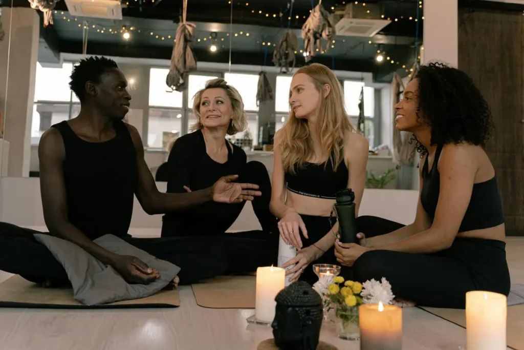 Groupe de pratiquants de yoga assis en cercle, discutant et partageant un moment convivial après une séance.