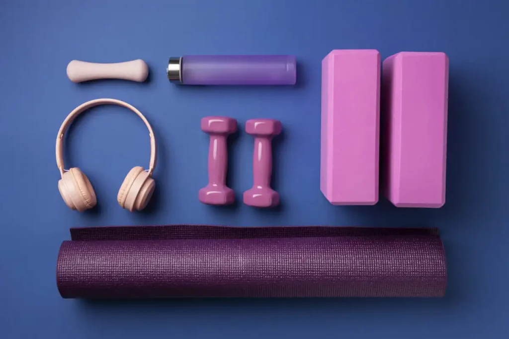 Équipement de yoga coloré : tapis, briques, haltères, écouteurs et gourde, idéal pour bien débuter sa pratique.