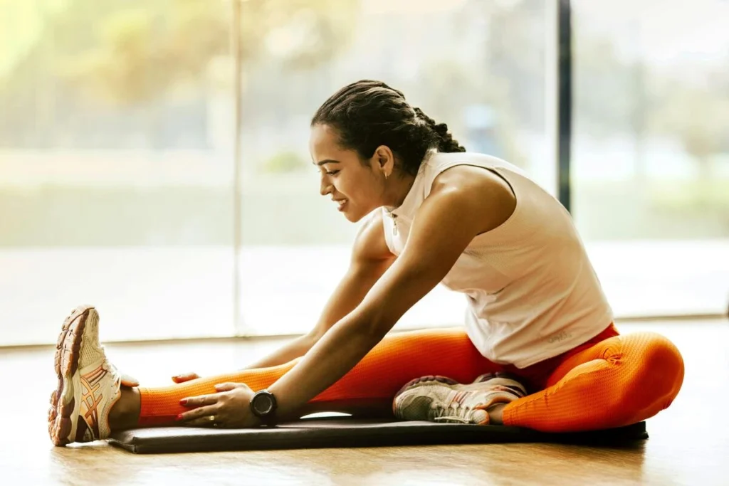 Femme souriante effectuant un étirement de yoga en intérieur.