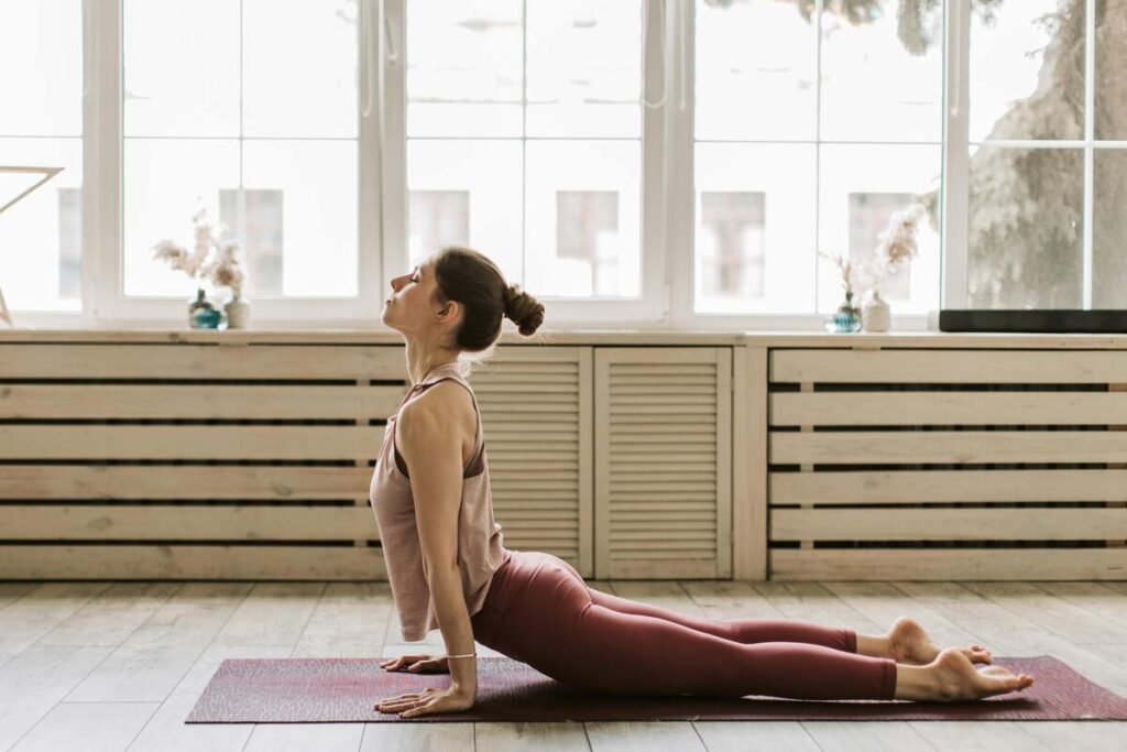 Femme en posture du cobra lors d’une séance de yoga en intérieur.